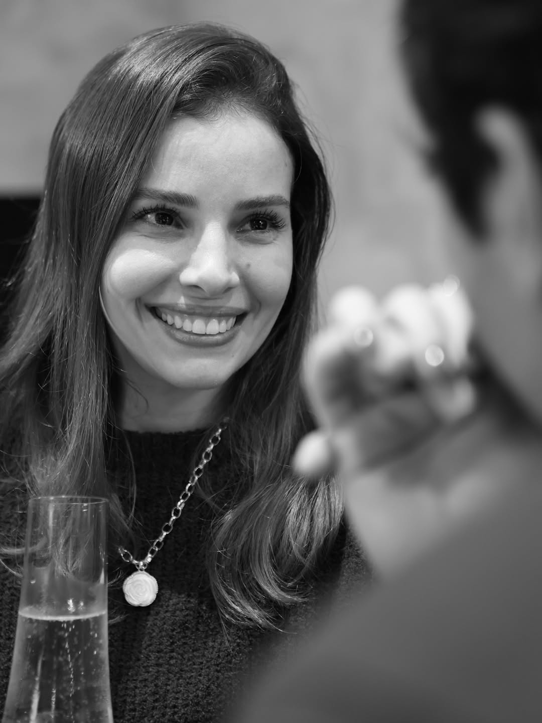 Retrato em preto e branco de uma mulher sorrindo com um anel em primeiro plano